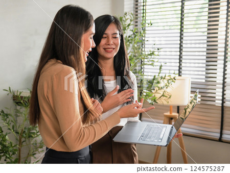 Two women are looking at a laptop together Two women are looking at a laptop together 124575287