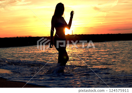 Silhouette of a woman at sunset by the water in Spain 124575911