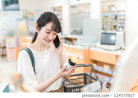 一位微笑的亞洲女性在藥房/藥店一邊打電話一邊購物 124575927