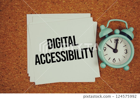 Digital Accessibility text on sticky note with alarm clock on cork paper background 124575992
