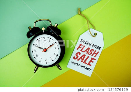 Flash Sale text on price tag with alarm clock top view on green geometric background Flash Sale text on price tag with alarm clock top view on green geometric background 124576129