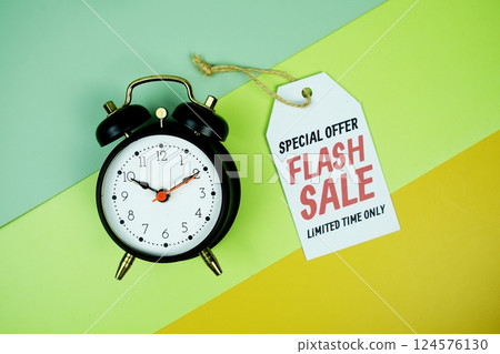 Flash Sale text on price tag with alarm clcok top view on green geometric background 124576130
