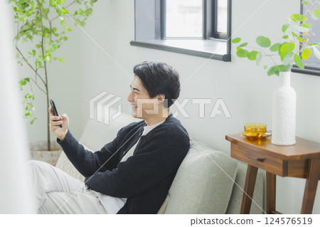 A man who uses a smartphone in the living room 124576519