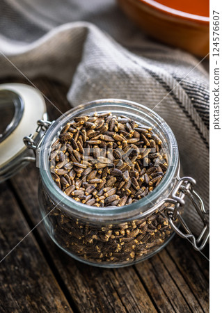 Milk thistle seeds in jar on wooden table. Milk thistle seeds in jar on wooden table. 124576607