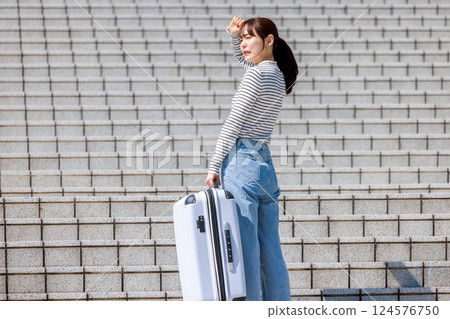 女人提著沉重的行李箱上樓梯 124576750