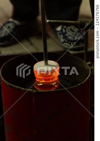 A mesmerizing close-up of a skilled artisan blowing molten glass into shape A mesmerizing close-up of a skilled artisan blowing molten glass into shape 124576766
