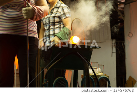 A glass blower is working on the manufacture of glass vases and glasses. A glass blower is working on the manufacture of glass vases and glasses. 124576768