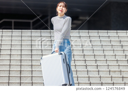 女人提著沉重的行李箱下樓梯 124576849