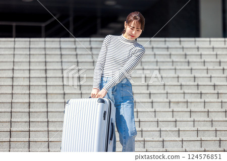 Woman carrying heavy suitcase down the stairs 124576851