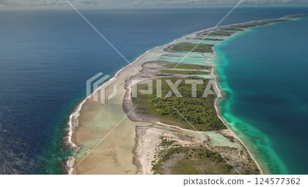 Aerial perspective reveals a beautiful coastal formation stretching into the ocean, surrounded by turquoise waters and lush greenery. The striking colors contrast beautifully with the sandy shoreline 124577362
