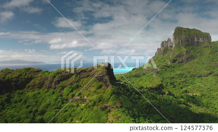 Mountain Otemanu dominates over green topical jungle landscape of Bora Bora volcanic island in French Polynesia, turquoise lagoon and coral reefs. Aerial drone view, bird fly over wild nature scene Mountain Otemanu dominates over green topical jungle landscape of Bora Bora volcanic island in French Polynesia, turquoise lagoon and coral reefs. Aerial drone view, bird fly over wild nature scene 124577376