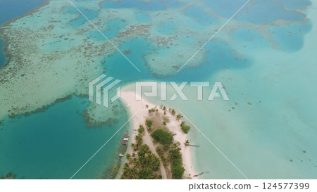 Aerial top down flight over Maupiti island's beauty: drone reveals white sand, turquoise coral reef ocean water, lush palm trees greenery, and colorful boats. Exotic tourist destination, summer travel 124577399