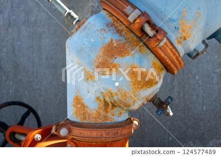 Rusty industrial water pipes with valves and connectors in an urban setting 124577489