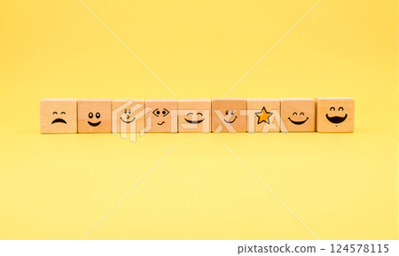 Smiley faces wooden blocks on yellow background symbolizing positive reviews, ratings feedback customer happiness satisfaction appreciation approval recognition emotions Smiley faces wooden blocks on yellow background symbolizing positive reviews, ratings feedback customer happiness satisfaction appreciation approval recognition emotions 124578115