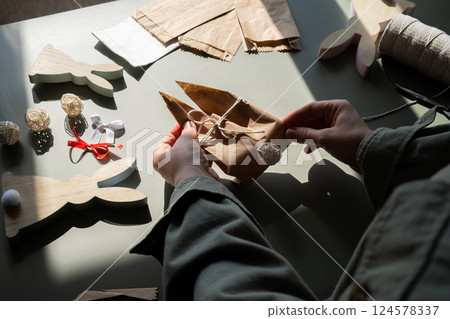 Step by step instruction of making handmade Easter gift bag rabbit bunny shaped sustainable materials decorations from craft paper. Female hands creating craft homemade present. Easter celebration 124578337