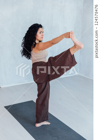 woman doing gymnastics yoga asana on the floor in the hall 124578476
