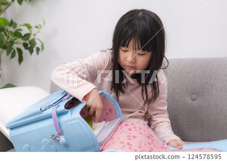 A first grade elementary school girl sitting with her school bag 124578595
