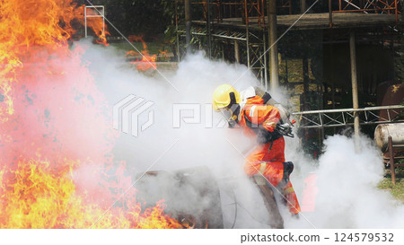 Firefighter fighting smoke flame use fire hose chemical water foam spray engine. Firefighter Rescue training in fire fighting extinguisher. Fireman wear hard hat safety suit uniform for protection Firefighter fighting smoke flame use fire hose chemical water foam spray engine. Firefighter Rescue training in fire fighting extinguisher. Fireman wear hard hat safety suit uniform for protection 124579532