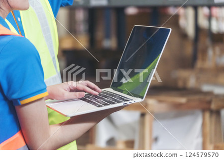 Warehouse management team using computer laptop check stock inventory. Asian men women worker use software computer type keyboard goods shelf. Teamwork logistics staff counting stock store inventory 124579570