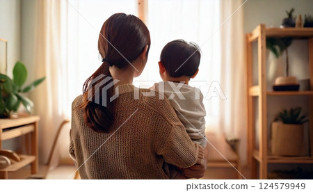Back view of a woman holding a child in her arms 124579949