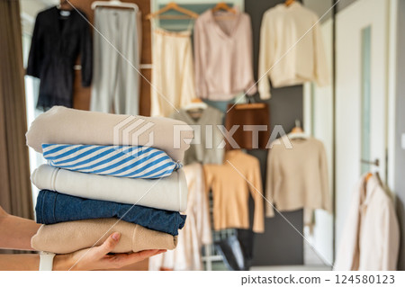 Stack of clothing in woman hands prepared for resale, donation, or recycling. Sustainable fashion choices support second-hand use, reduce waste, and promote conscious consumption 124580123
