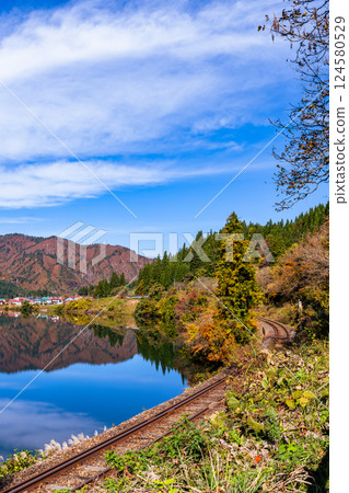 Fukushima, JAPAN - Nov 10, 2024: Tadami Line train tracts run along Tadami Riverside in autumn at Aizu-Kawaguchi, Mishima, Fukushima Fukushima, JAPAN - Nov 10, 2024: Tadami Line train tracts run along Tadami Riverside in autumn at Aizu-Kawaguchi, Mishima, Fukushima 124580529