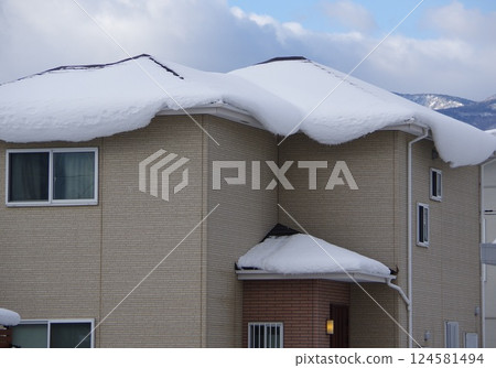 Snow cornice on the roof of a house 124581494