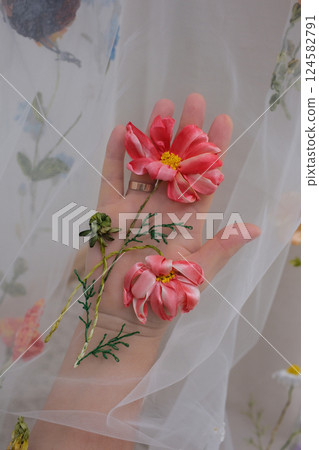 tulle fabric embroidery of flowers and birds on a veil On a thin fabric a woman embroiders straightening beautiful handwork on a mannequin wedding dress with bright decorations tulle fabric embroidery of flowers and birds on a veil On a thin fabric a woman embroiders straightening beautiful handwork on a mannequin wedding dress with bright decorations 124582791