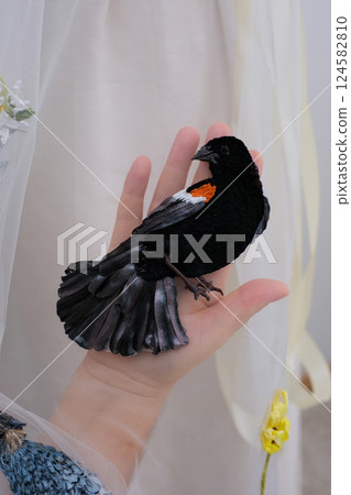 tulle fabric embroidery of flowers and birds on a veil On a thin fabric a woman embroiders straightening beautiful handwork on a mannequin wedding dress with bright decorations tulle fabric embroidery of flowers and birds on a veil On a thin fabric a woman embroiders straightening beautiful handwork on a mannequin wedding dress with bright decorations 124582810