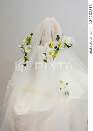 tulle fabric embroidery of flowers and birds on a veil On a thin fabric a woman embroiders straightening beautiful handwork on a mannequin wedding dress with bright decorations tulle fabric embroidery of flowers and birds on a veil On a thin fabric a woman embroiders straightening beautiful handwork on a mannequin wedding dress with bright decorations 124582811