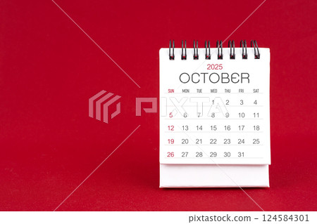 White desk calendar for October 2025 on red background. 124584301