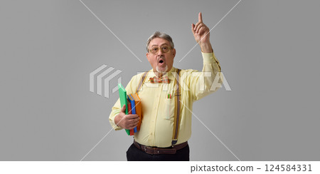 Expressive elderly man, teacher raising finger and speaking with emotion while holding colorful folders. Passionate explanation, learning Expressive elderly man, teacher raising finger and speaking with emotion while holding colorful folders. Passionate explanation, learning 124584331