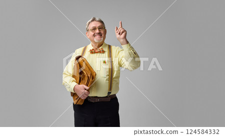 Elderly academic holding leather briefcase and raising index finger with knowing smile. Idea moment, important insight. 124584332