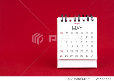White desk calendar for May 2025 on red background. White desk calendar for May 2025 on red background. 124584357