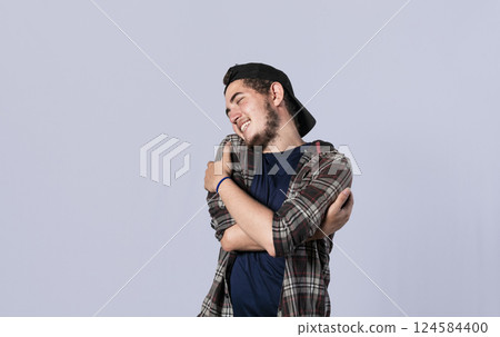 Friendly man hugging himself, Pleased young man hugging himself, Attractive positive looking friendly young man with a sincere smile embracing himself gratefully Friendly man hugging himself, Pleased young man hugging himself, Attractive positive looking friendly young man with a sincere smile embracing himself gratefully 124584400