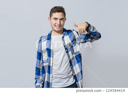 Smiling guy pointing down with one hand isolated, Concept of young man recommending a product isolated. Smiling latin guy pointing with a hand down, Amazed young man pointing down Smiling guy pointing down with one hand isolated, Concept of young man recommending a product isolated. Smiling latin guy pointing with a hand down, Amazed young man pointing down 124584414