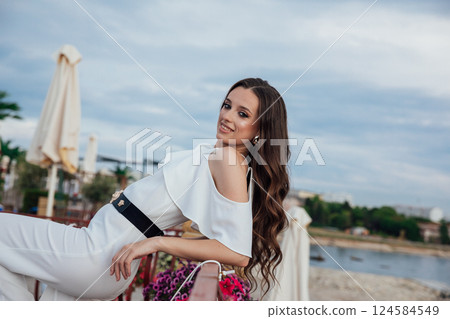 Beautiful slim woman in white suit on the beach by the sea 124584549