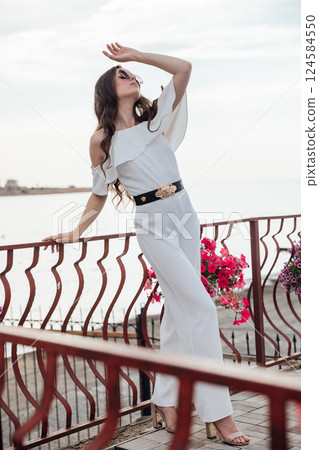 Beautiful slim woman in white suit on the beach by the sea 124584550