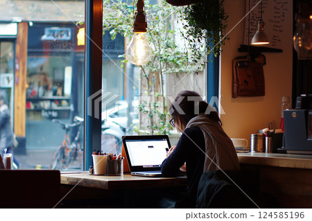 Woman working on laptop at cozy cafe. AI-generated item 124585196