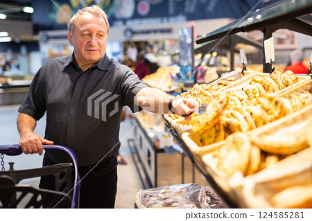 Man takes muffins on shelf of bakery section Man takes muffins on shelf of bakery section 124585281