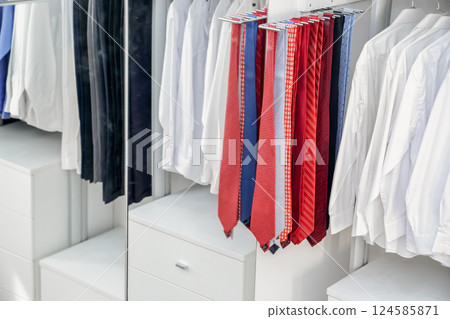 A collection of pristine white shirts, trousers, and ties stood out against a wall of colorful accessories, ranging from bold primary shades to subtle pastels. A collection of pristine white shirts, trousers, and ties stood out against a wall of colorful accessories, ranging from bold primary shades to subtle pastels. 124585871