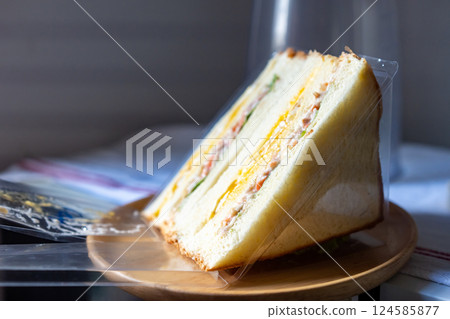 Homemade Sandwich, fried egg with crab stick, vegetable salad and mayonnaise served on a circular wooden dish. 124585877
