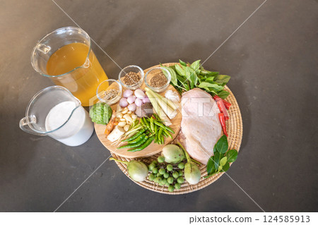 Flatlay top table of Performing ingredient, seasoning of Chicken Green Curry and Ingredient, garlic, shallot, galangal, lemon grass, basil, bergamot, Thai eggplant. 124585913