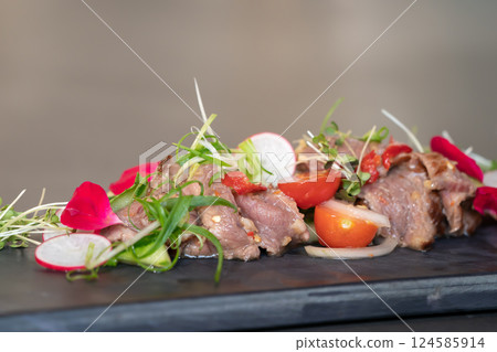 Close up to Spicy Thai Beef Salad garnished on top with cress and micro herb was put on a rectangular stone plate. Close up to Spicy Thai Beef Salad garnished on top with cress and micro herb was put on a rectangular stone plate. 124585914