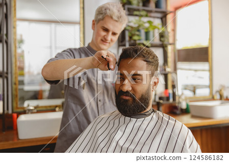 A skilled barber is expertly styling a clients hair in a modern, fashionable hair salon setting 124586182
