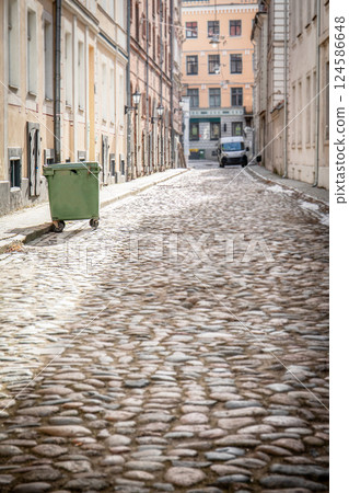 Cobblestone Street with Green Trash Bin and Historic Buildings 124586648