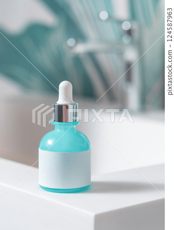 Blue glass dropper bottle with pipette on washbasin in green bathroom close up cosmetic mockup 124587963