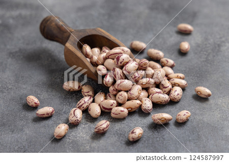 Wooden scoop full of dried pinto beans on gray closeup. Traditional Latin American legumes Wooden scoop full of dried pinto beans on gray closeup. Traditional Latin American legumes 124587997