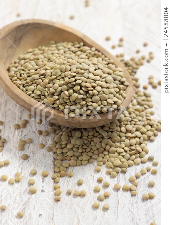 Wooden bowl full of dried green lentils on white table closeup. Traditional mediterranean legume Wooden bowl full of dried green lentils on white table closeup. Traditional mediterranean legume 124588004