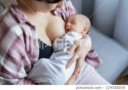 Newborn baby peacefully sleeping after breastfeeding in warm mother embrace at home. No face mother breastfeeding and hugging baby. Lactation infant concept. Baby eating milk before he sleeping. Newborn baby peacefully sleeping after breastfeeding in warm mother embrace at home. No face mother breastfeeding and hugging baby. Lactation infant concept. Baby eating milk before he sleeping. 124588039